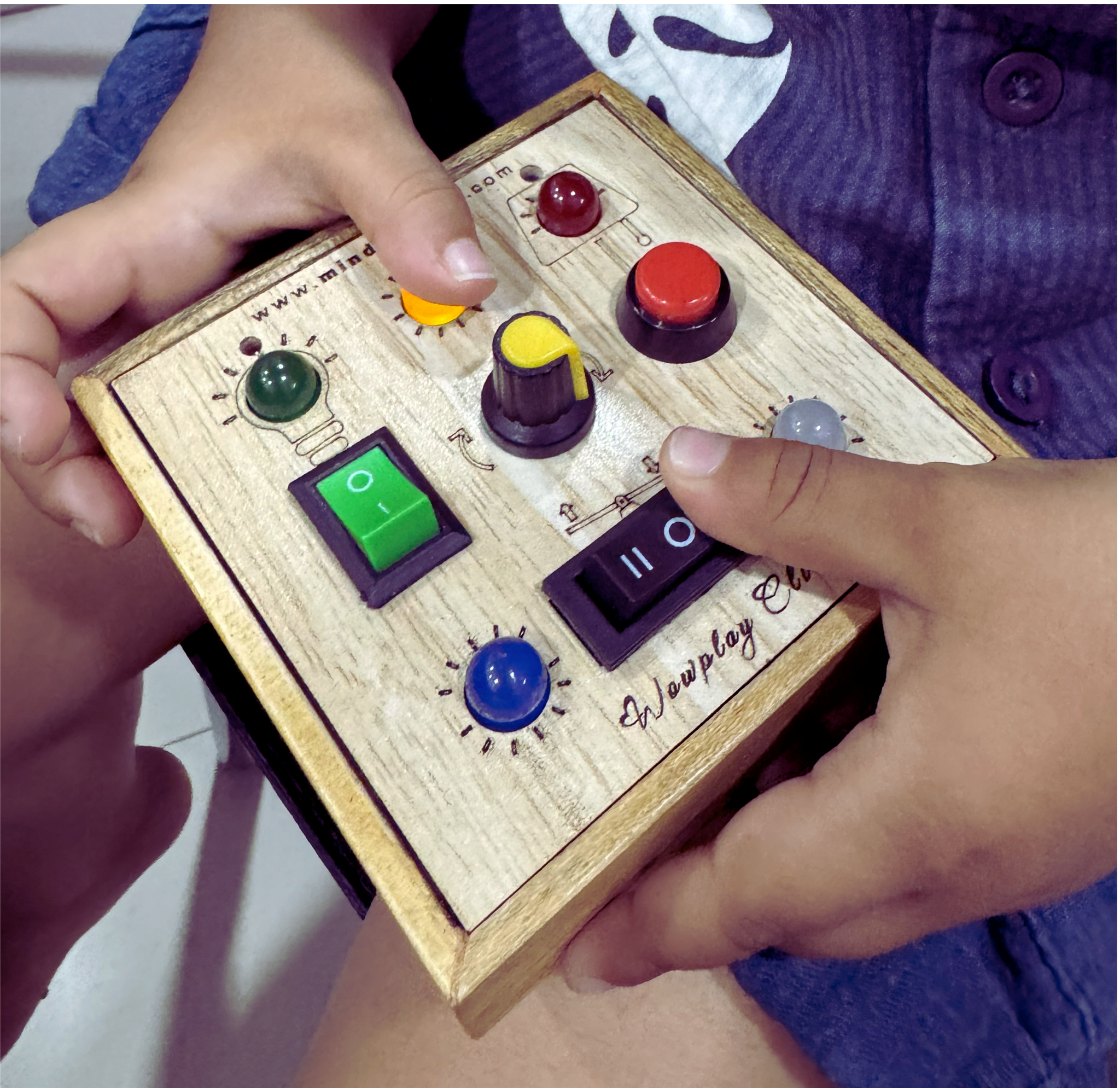 Two toddler hands exploring multiple buttons and switches together on the busyboard