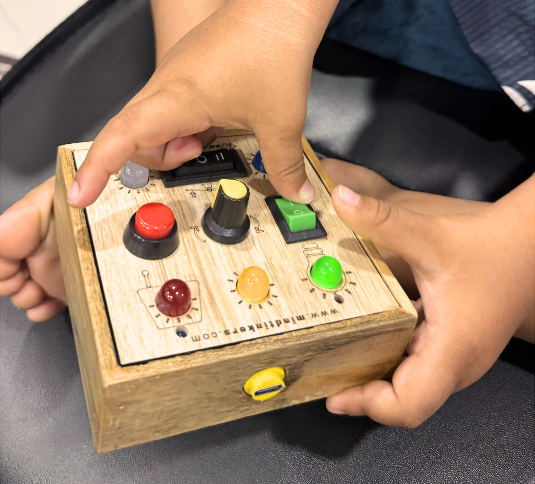 Close-up of a toddler's hand flipping a green switch on the busyboard