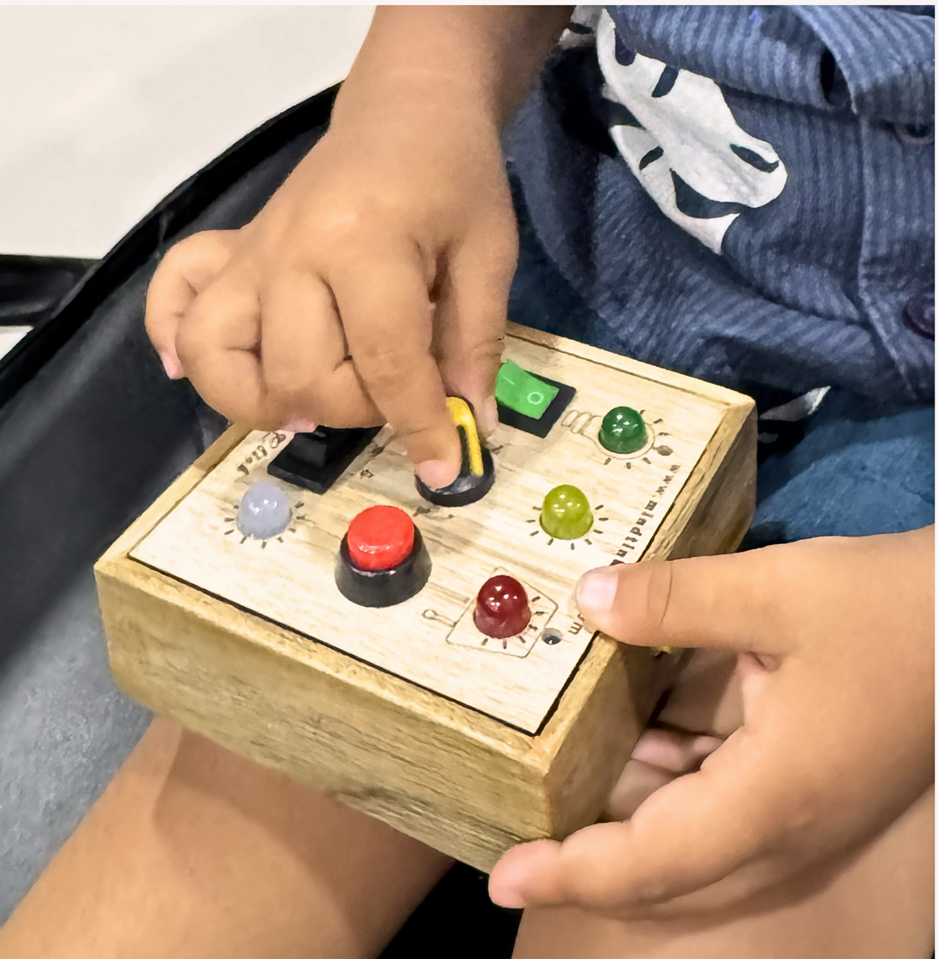 Close-up of a toddler's hand turning the yellow rotating knob on the busyboard