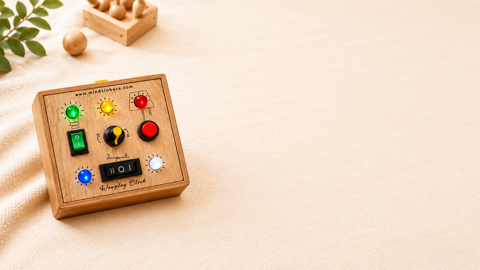 WowPlay Click wooden busyboard resting on a woven cushion, angled to show all its buttons, switches and knob